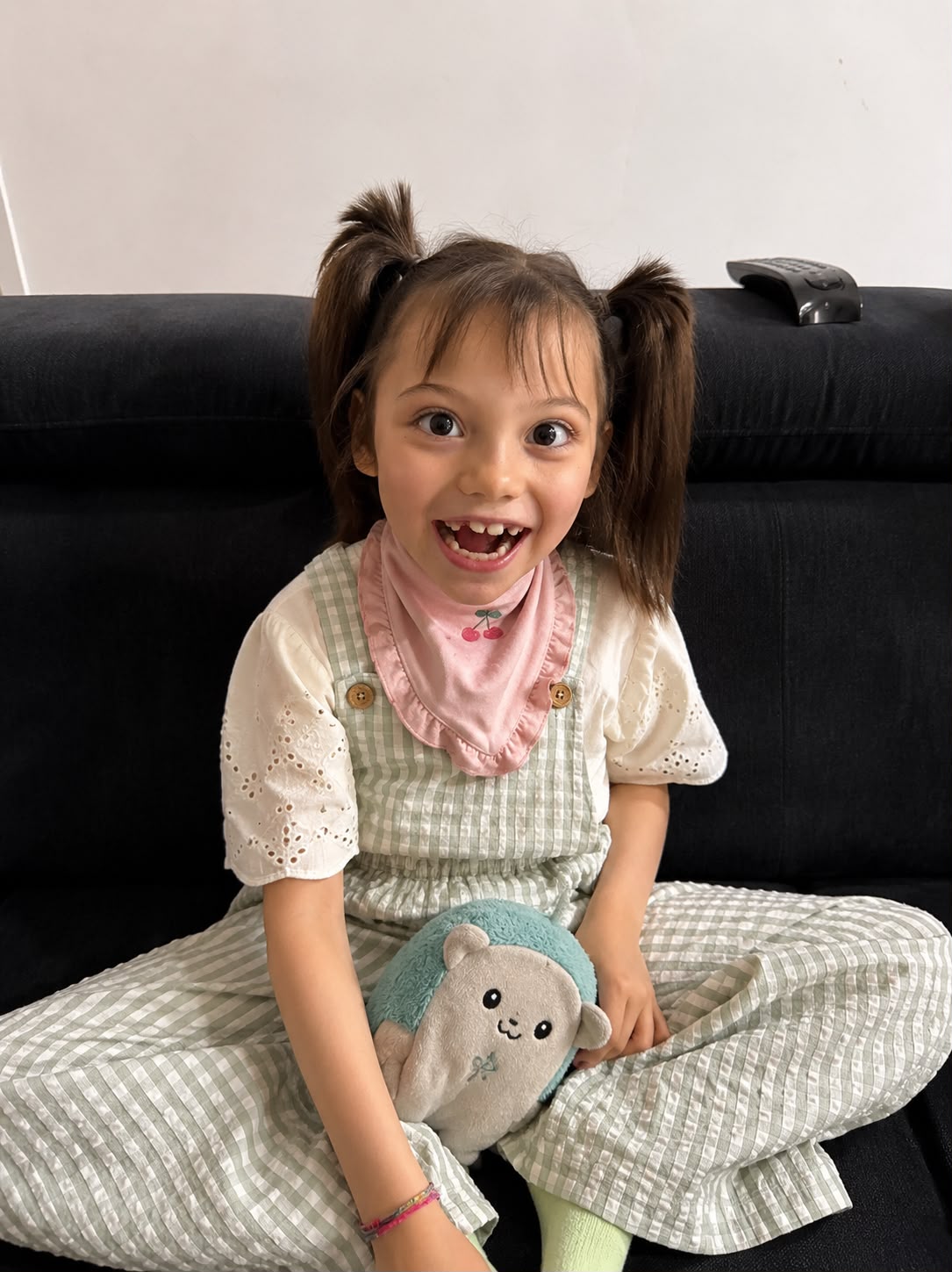 Leonor Lopes sentada no sofá a sorrir, com um brinquedo no colo